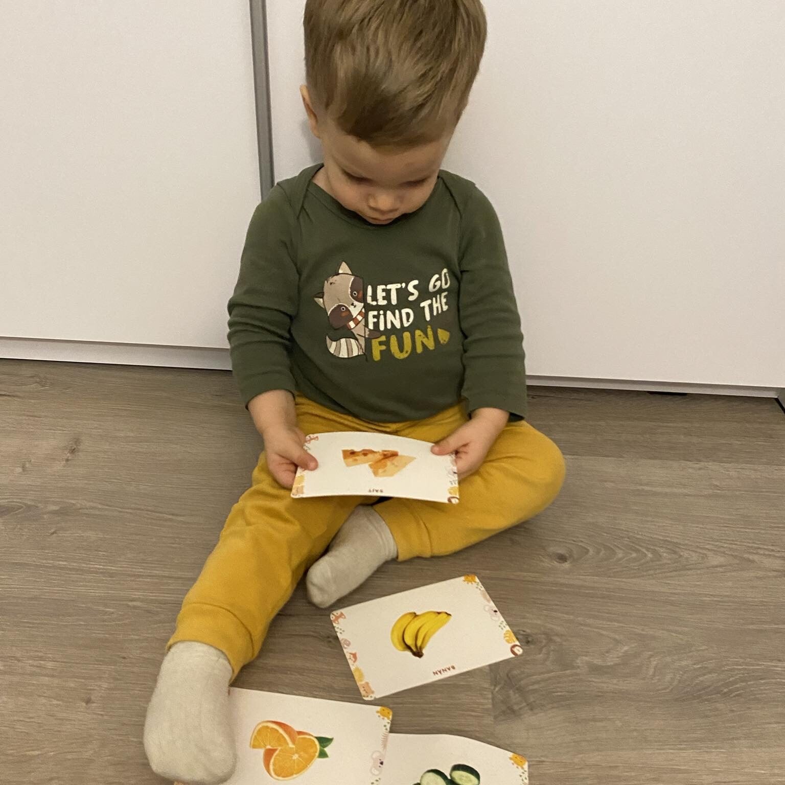 Baba nézegeti a Csemete Jelek babajelbeszédkártyákat. Sajtos babajel kártya van a kezében.